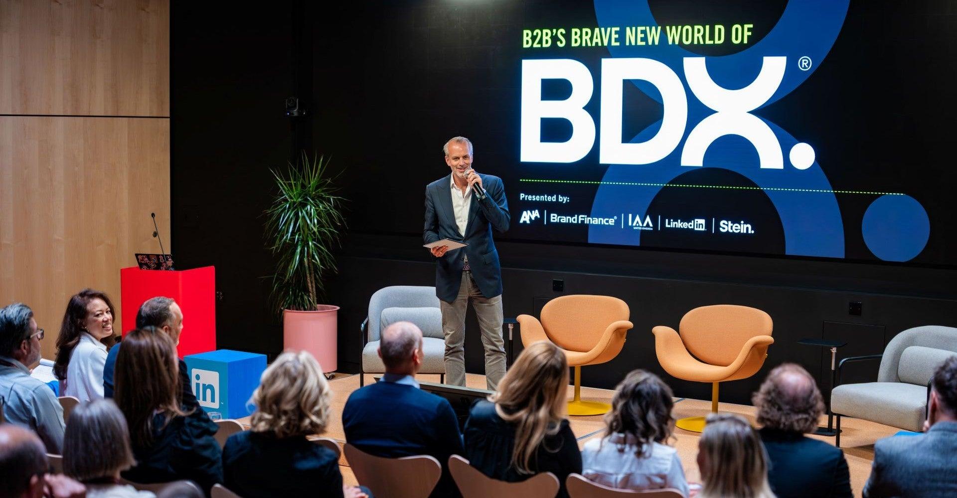 Man on stage with some of the crowd shown, event branding "The Brave New World of BDX" displayed